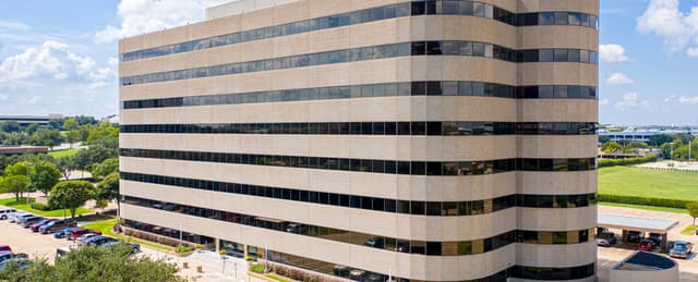 Eight-story office building in Irving, Texas, recently sold in a Matthews™-represented transaction, featuring beige exterior panels and horizontal strip windows with adjacent parking and landscaping.